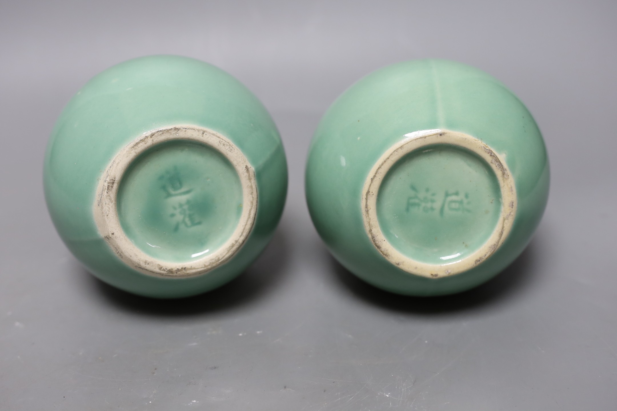 A pair of Chinese celadon ground bottle vases 21cm tall